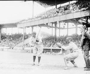 Ty Cobb Stands In A Batting Stance As A Catcher Crouches Behind Him And A Crowded Grandstand Fills The Background