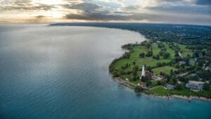 Aerial Photography Of Body Of Water Near Grass Filed With Trees