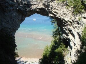 A Rock Arch With Trees And A Body Of Water In The Background With Mackinac Island In The Background