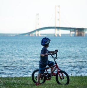 A Child On A Bicycle By A Body Of Water