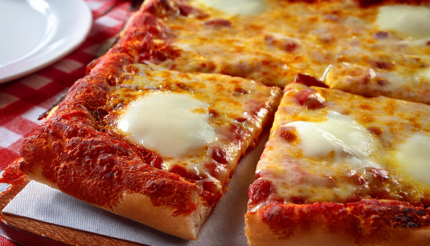 a square pizza with cheese and sauce on a table