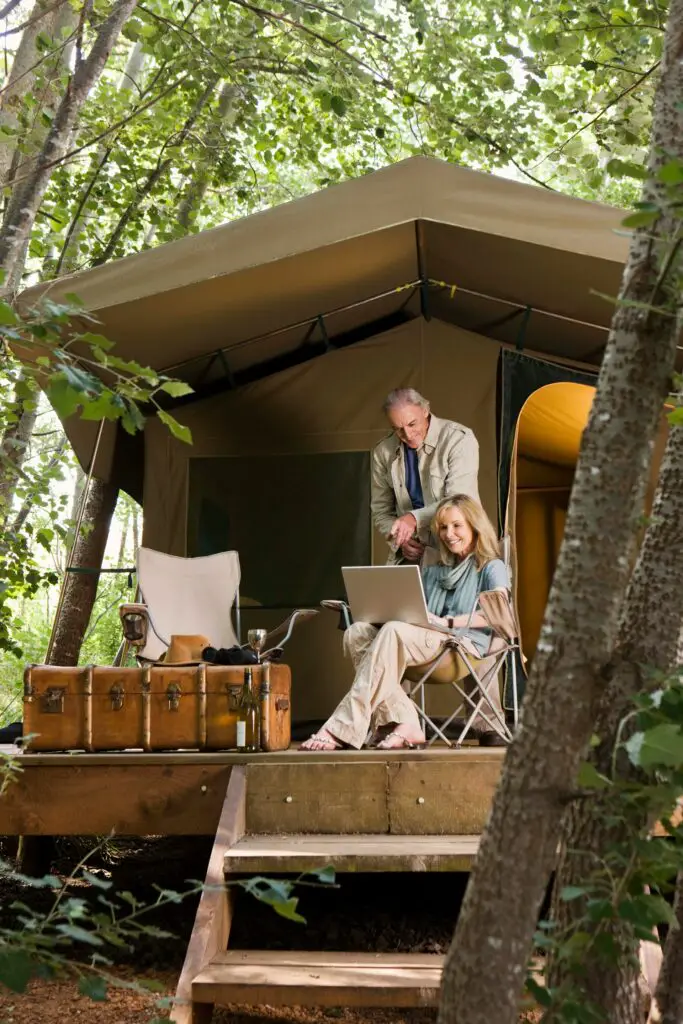 A Man And Woman Sitting In A Chair Outside Of A Tent