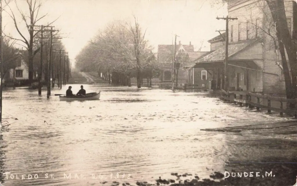 A Couple Of People In A Boat In A Flooded Street