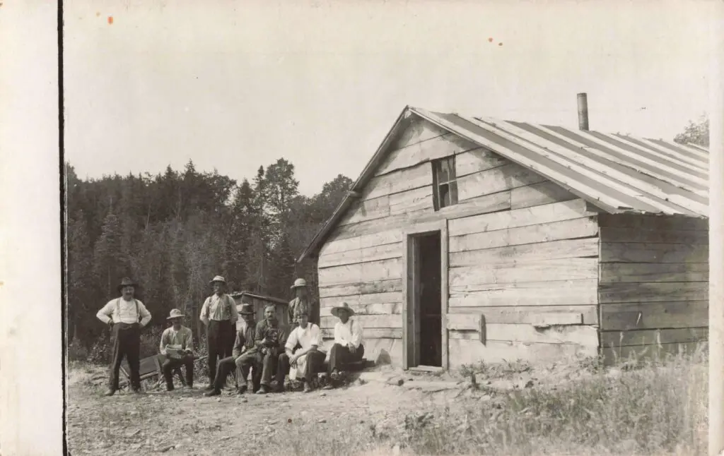 A Group Of Men Standing Outside Of A Wooden Building
