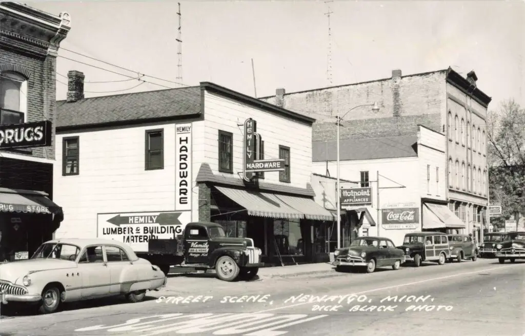 A Black And White Photo Of A Street With Cars Parked On The Side
