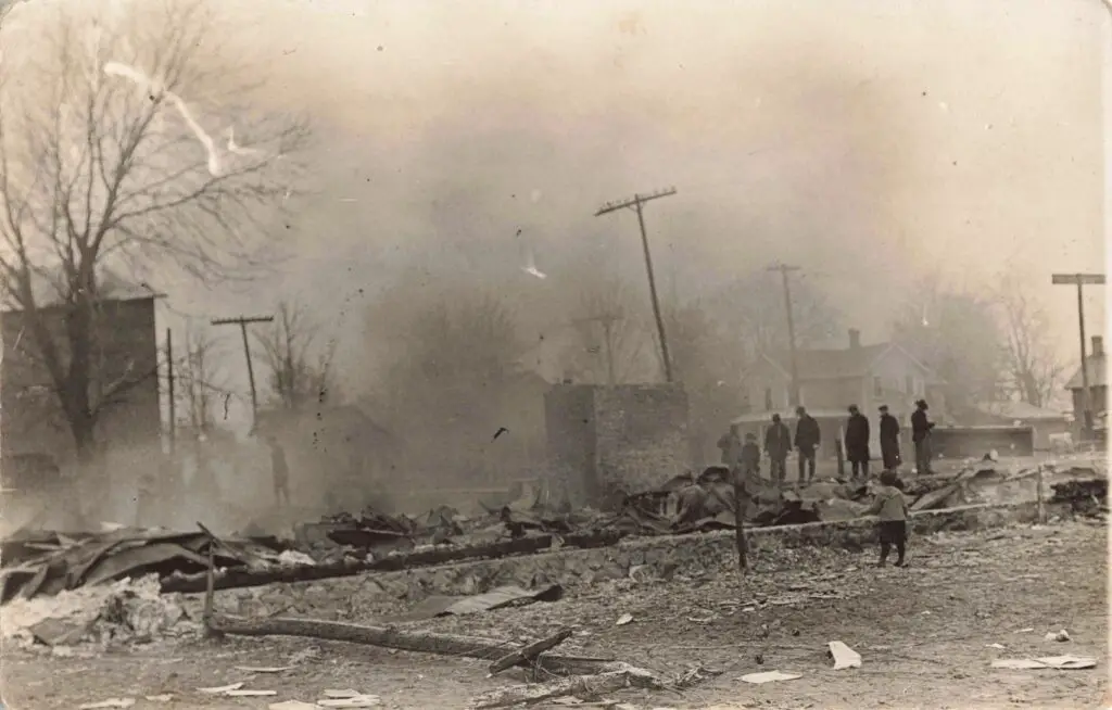 A Group Of People Standing In Front Of A Destroyed Building