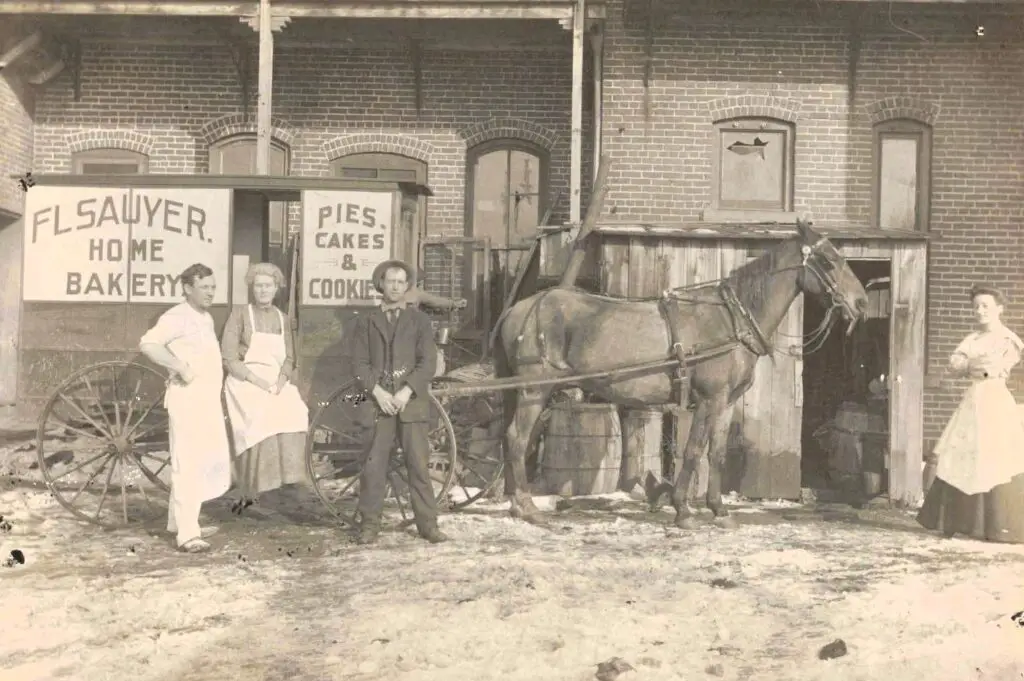 A Group Of People Standing In Front Of A Horse Drawn Carriage