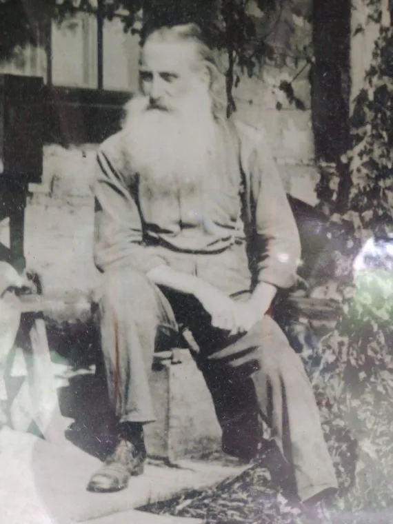 A Man With A Long Beard Sitting On A Chair