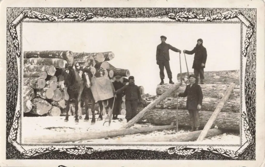 A Group Of Men Standing Next To A Pile Of Logs