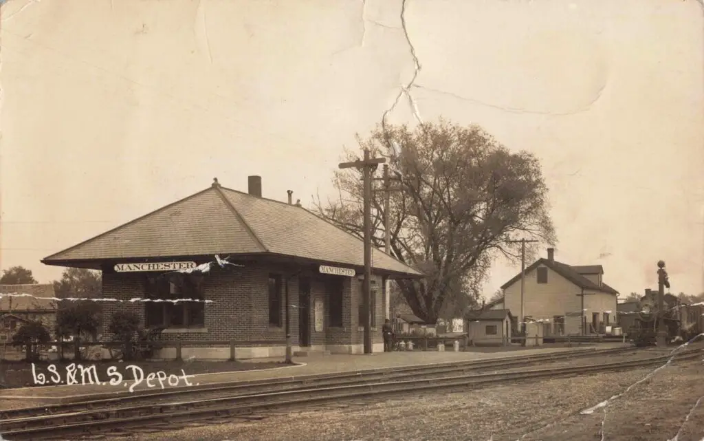 A Train Station With A Building And Train Tracks