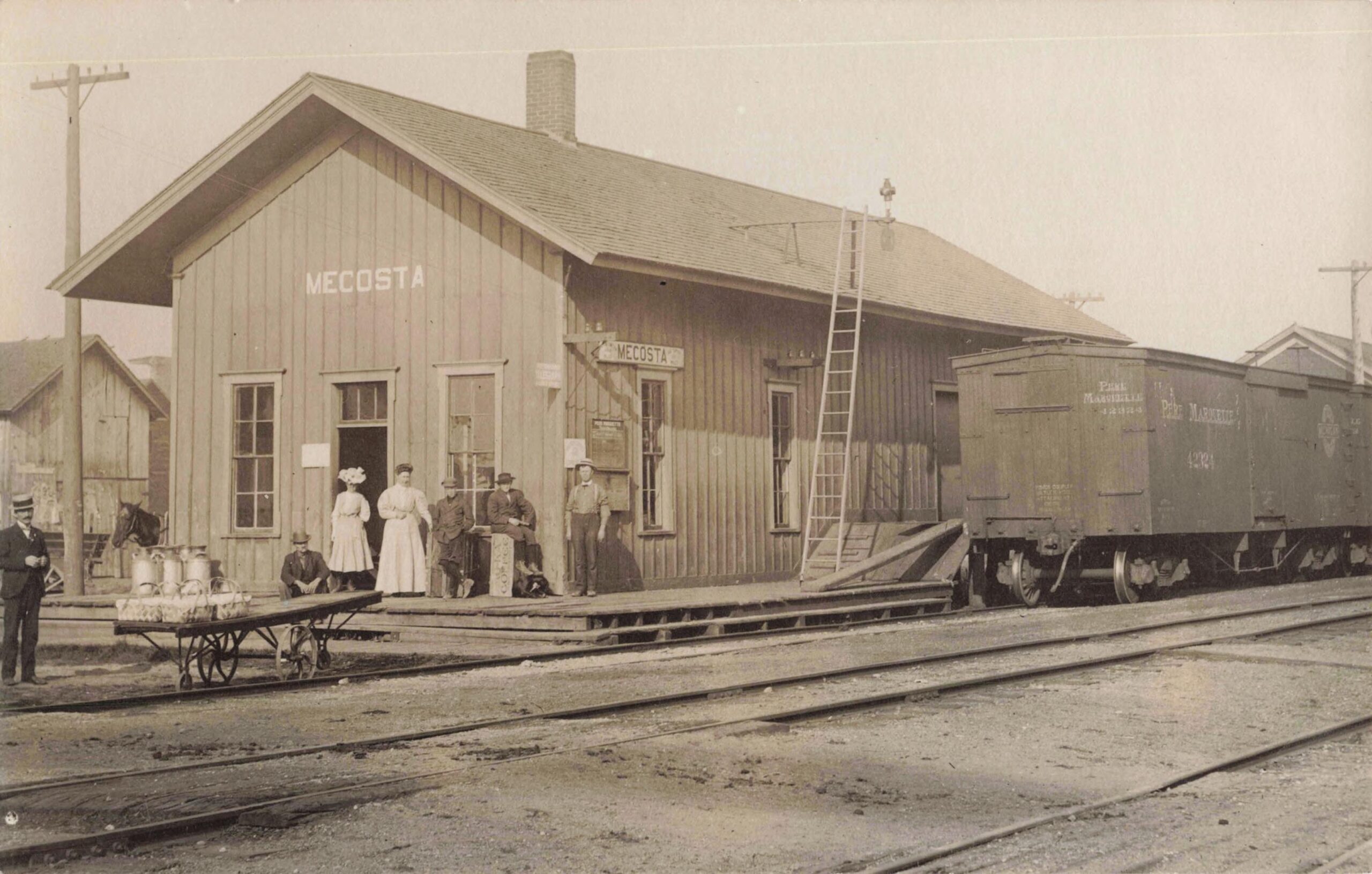 Pere Marquette Railroad Depot At Mecosta With Passengers, Milk Cans, A Platform Cart And A Freight Car