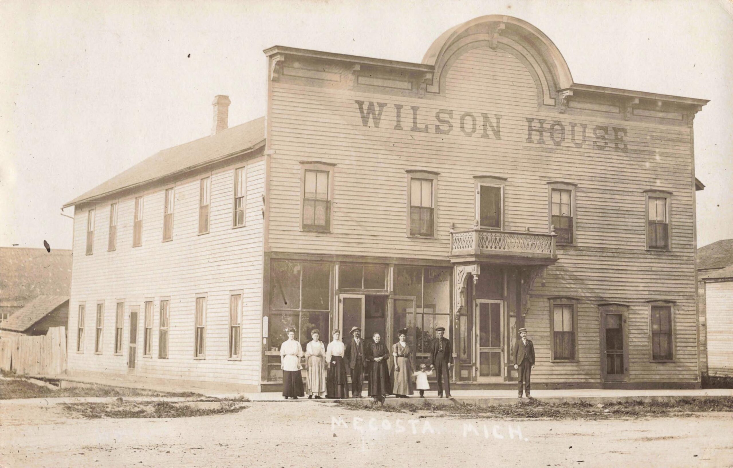 A Group Of Men, Women And Children Posed On The Porch And Lawn Of The Wilson House Hotel In Mecosta